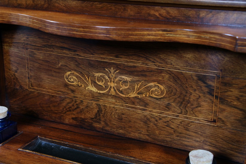 A late Victorian inlaid rosewood bonheur du jour writing desk featuring a green leather surface, raised gallery shelf, and tapered legs with brass castors. View X