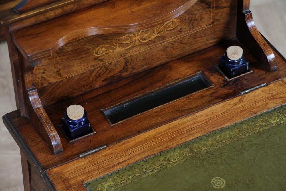 A late Victorian inlaid rosewood bonheur du jour writing desk featuring a green leather surface, raised gallery shelf, and tapered legs with brass castors. View XV