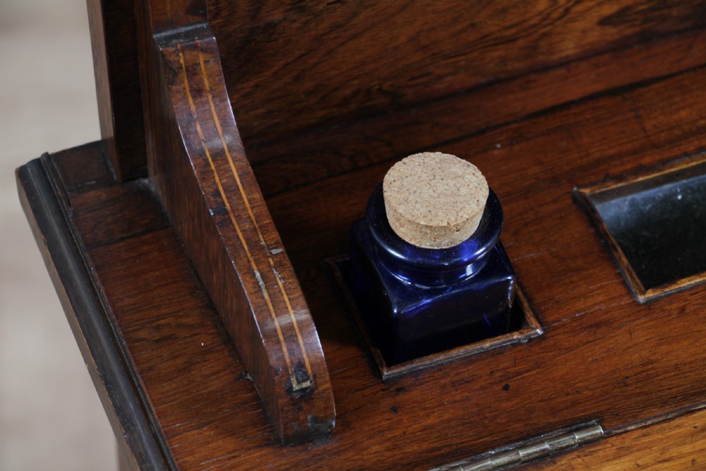 A late Victorian inlaid rosewood bonheur du jour writing desk featuring a green leather surface, raised gallery shelf, and tapered legs with brass castors. View XVI