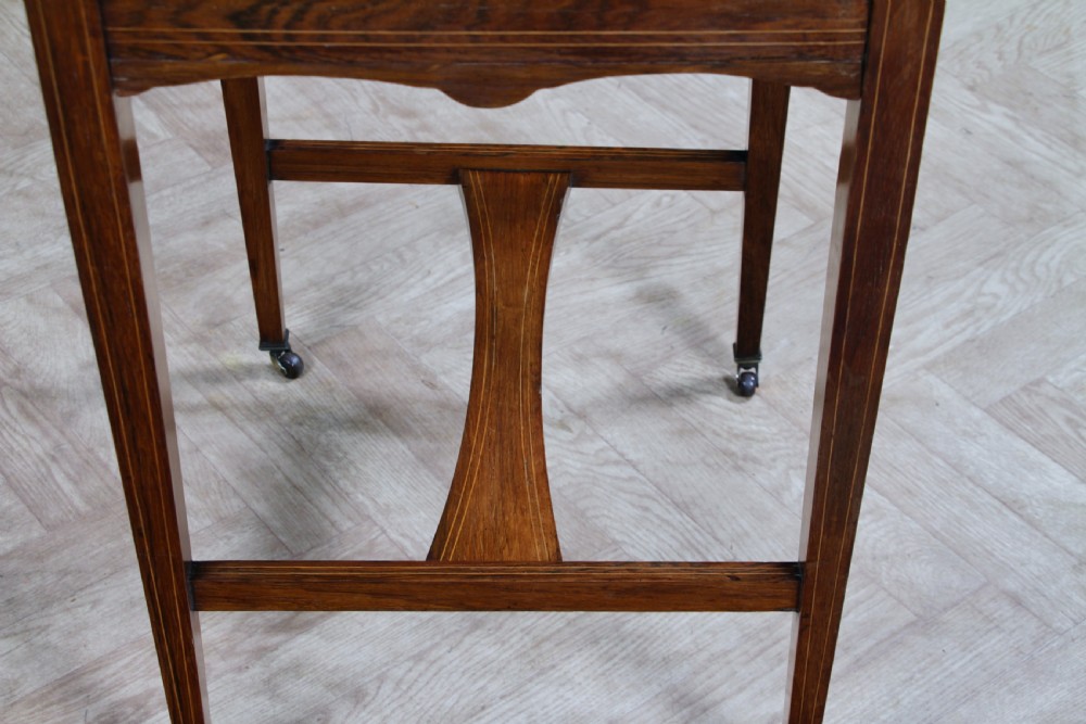 A late Victorian inlaid rosewood bonheur du jour writing desk featuring a green leather surface, raised gallery shelf, and tapered legs with brass castors. View XVII