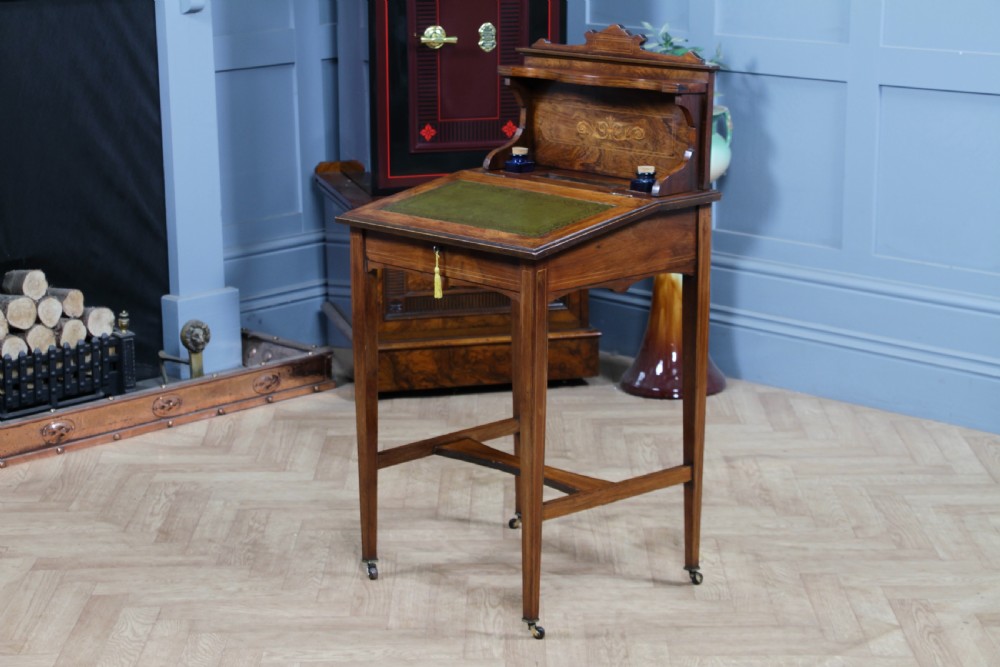 A late Victorian inlaid rosewood bonheur du jour writing desk featuring a green leather surface, raised gallery shelf, and tapered legs with brass castors. View XIX
