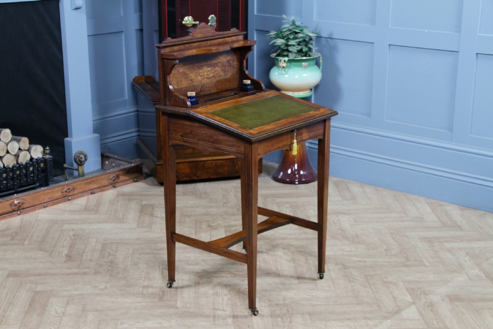 A late Victorian inlaid rosewood bonheur du jour writing desk featuring a green leather surface, raised gallery shelf, and tapered legs with brass castors. View XX