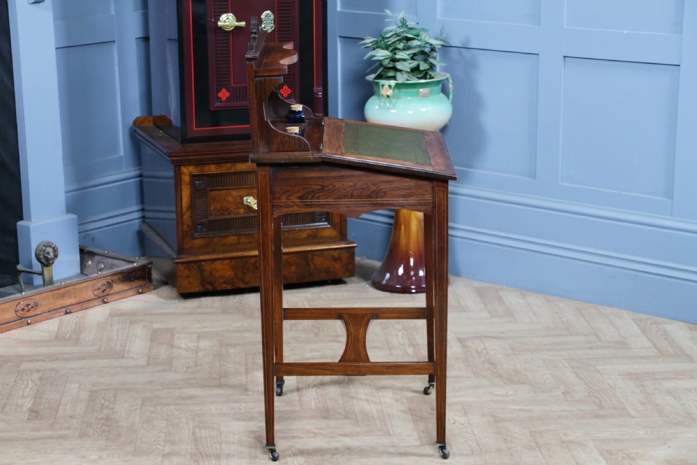 A late Victorian inlaid rosewood bonheur du jour writing desk featuring a green leather surface, raised gallery shelf, and tapered legs with brass castors. View XXI