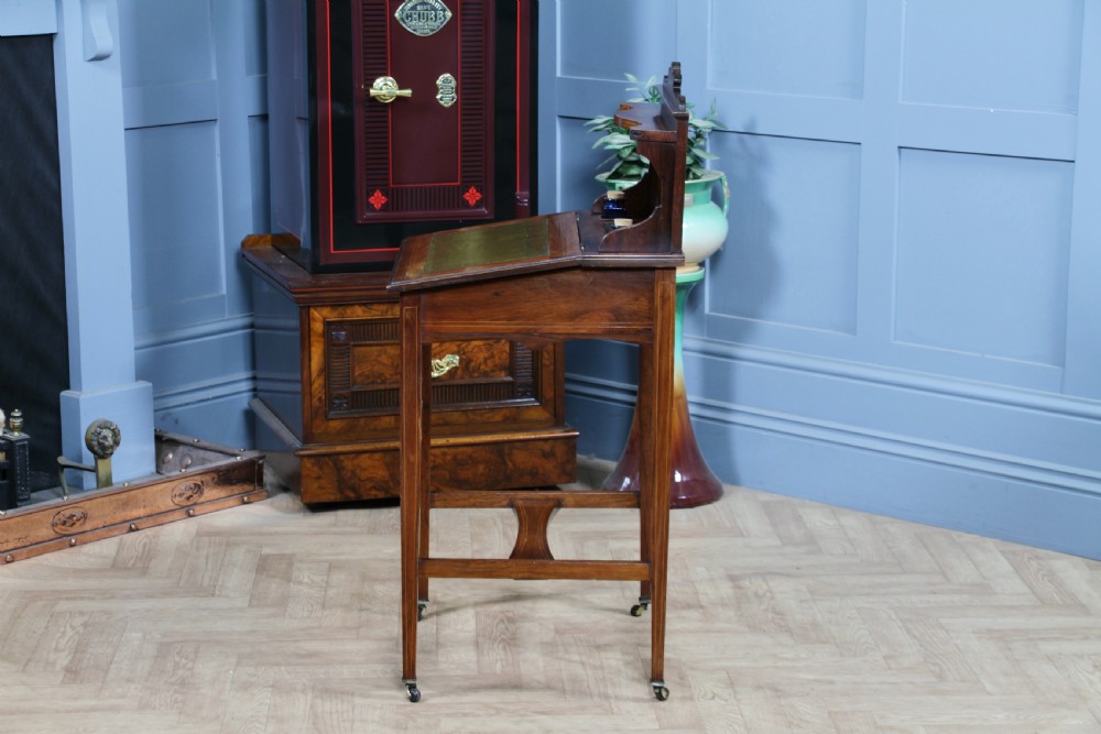A late Victorian inlaid rosewood bonheur du jour writing desk featuring a green leather surface, raised gallery shelf, and tapered legs with brass castors. View XXII