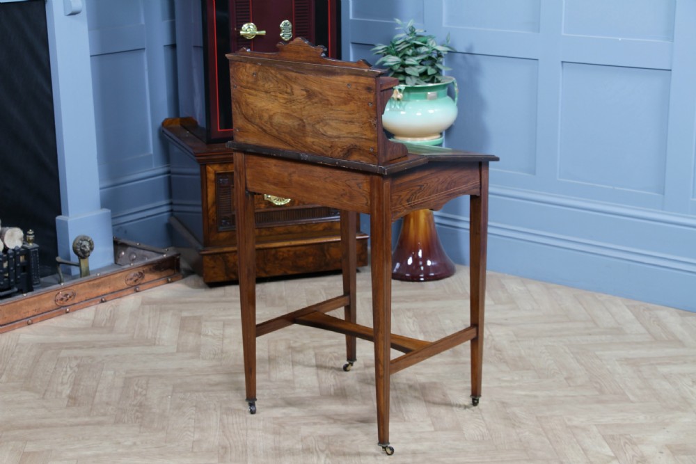 A late Victorian inlaid rosewood bonheur du jour writing desk featuring a green leather surface, raised gallery shelf, and tapered legs with brass castors. View XXIII