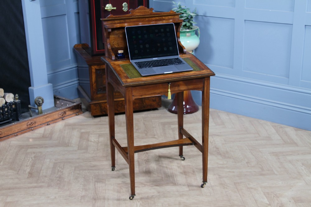 A late Victorian inlaid rosewood bonheur du jour writing desk featuring a green leather surface, raised gallery shelf, and tapered legs with brass castors. View XXIV