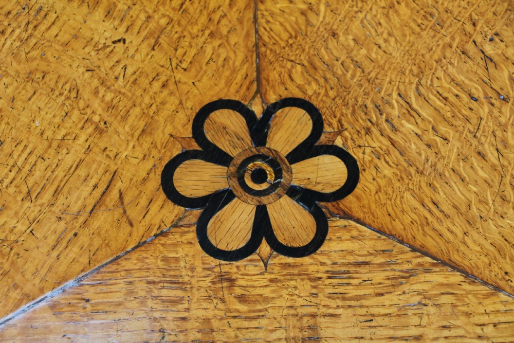 A Victorian Aesthetic Movement oak handkerchief table featuring ebonised accents, curved legs, and a triangular drop-leaf top with a central inlaid floral motif. View VI