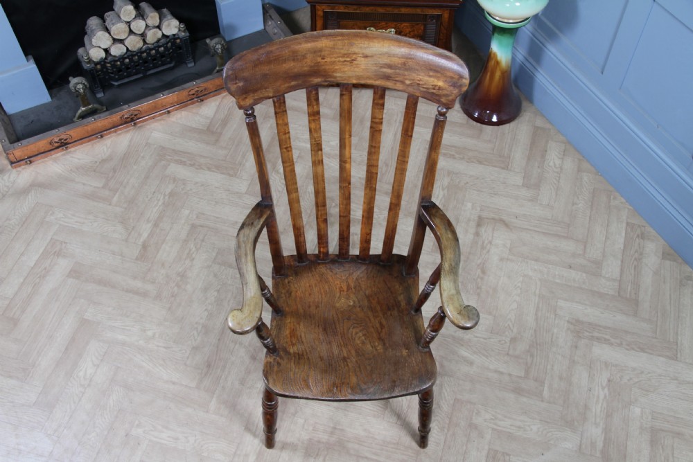 An antique Victorian lathe back armchair crafted from warm brown timber with turned legs and a solid shaped seat. View IV