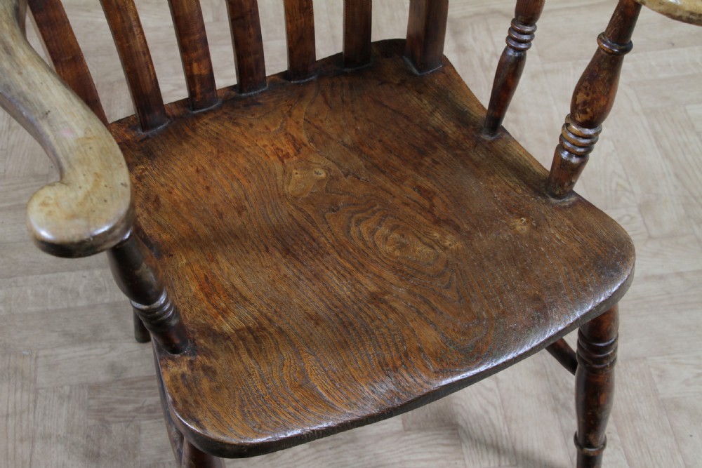 An antique Victorian lathe back armchair crafted from warm brown timber with turned legs and a solid shaped seat. View V