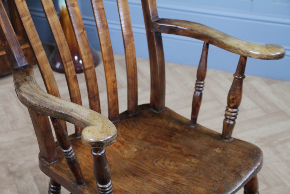 An antique Victorian lathe back armchair crafted from warm brown timber with turned legs and a solid shaped seat. View VI