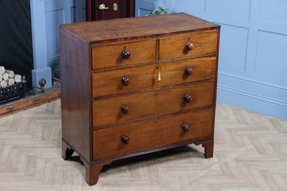 A restored Georgian mahogany chest of five drawers featuring two short drawers over three long drawers with turned wooden knobs and bracket feet.