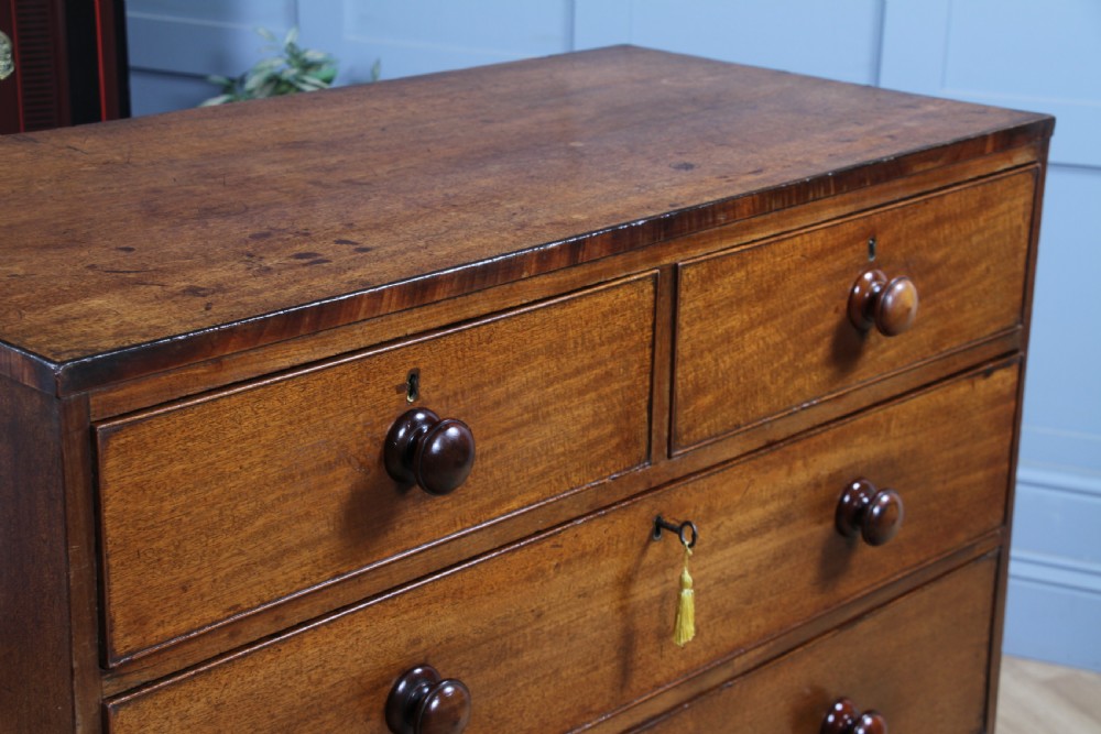 A restored Georgian mahogany chest of five drawers featuring two short drawers over three long drawers with turned wooden knobs and bracket feet. View V