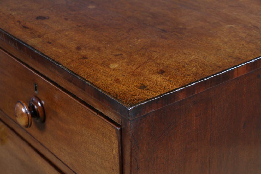 A restored Georgian mahogany chest of five drawers featuring two short drawers over three long drawers with turned wooden knobs and bracket feet. View VII