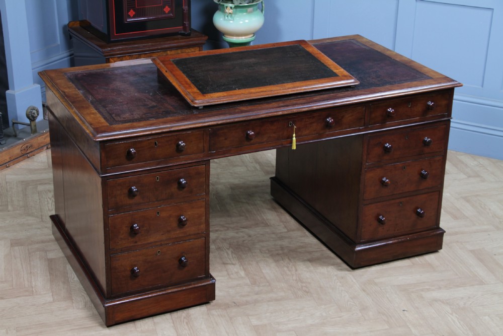 A Victorian mahogany pedestal desk featuring twin drawer pedestals, a dark leather writing inset, and a matching angled writing slope. View II
