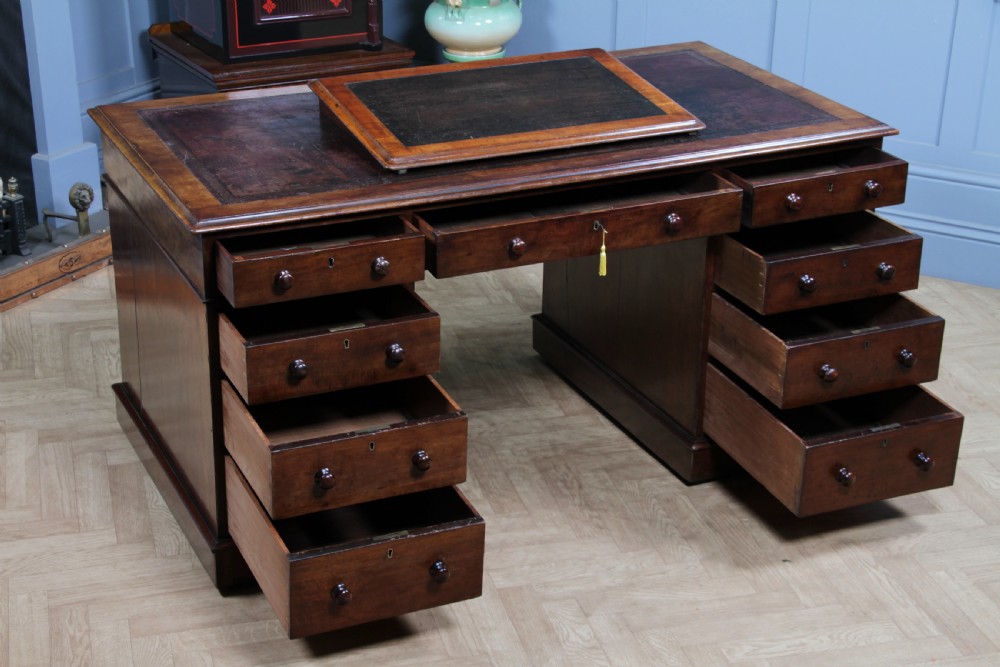 A Victorian mahogany pedestal desk featuring twin drawer pedestals, a dark leather writing inset, and a matching angled writing slope. View III