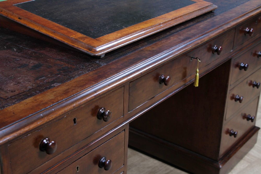 A Victorian mahogany pedestal desk featuring twin drawer pedestals, a dark leather writing inset, and a matching angled writing slope. View IV