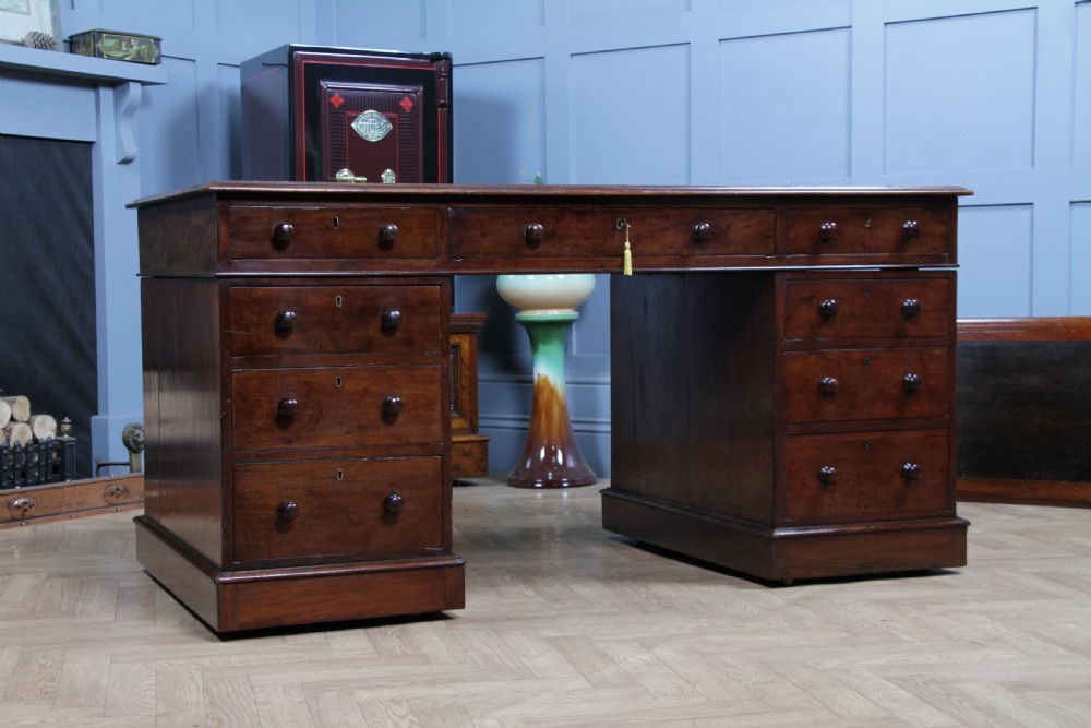 A Victorian mahogany pedestal desk featuring twin drawer pedestals, a dark leather writing inset, and a matching angled writing slope. View V