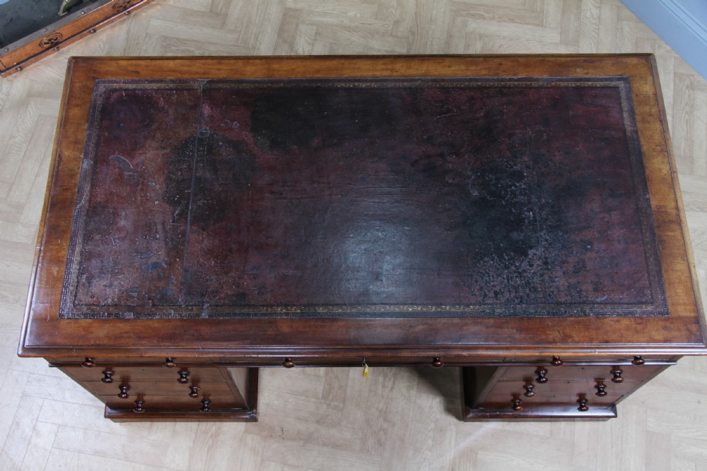 A Victorian mahogany pedestal desk featuring twin drawer pedestals, a dark leather writing inset, and a matching angled writing slope. View VII