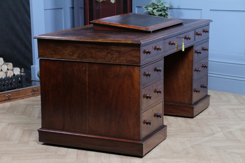 A Victorian mahogany pedestal desk featuring twin drawer pedestals, a dark leather writing inset, and a matching angled writing slope. View XV