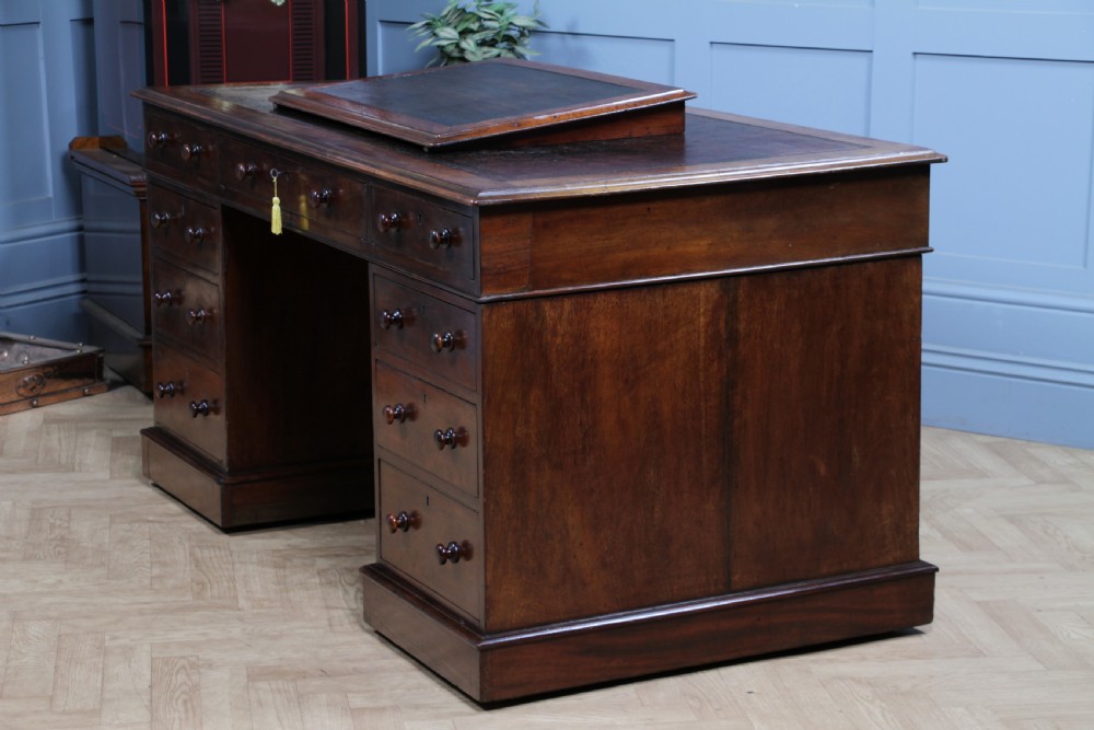A Victorian mahogany pedestal desk featuring twin drawer pedestals, a dark leather writing inset, and a matching angled writing slope. View XVI