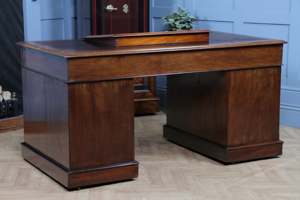 A Victorian mahogany pedestal desk featuring twin drawer pedestals, a dark leather writing inset, and a matching angled writing slope. View XVII