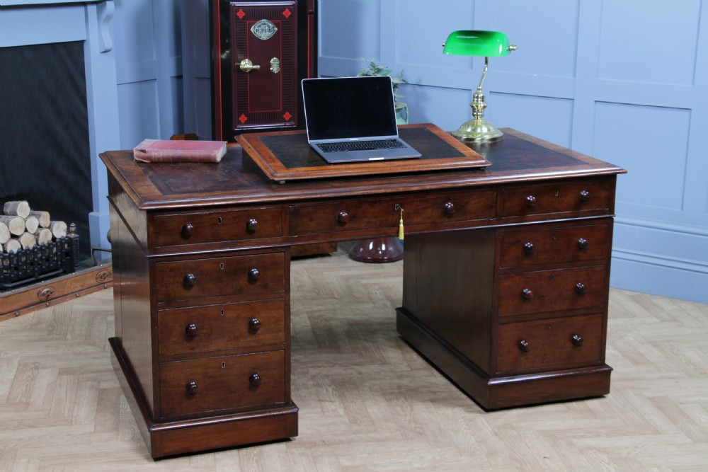 A Victorian mahogany pedestal desk featuring twin drawer pedestals, a dark leather writing inset, and a matching angled writing slope. View XX