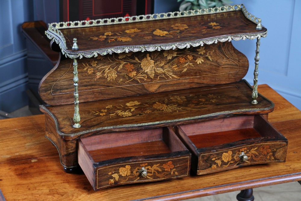 A French Napoleon III rosewood tabletop etagere featuring two tiered shelves decorated with floral marquetry, gilt metal mounts, a gallery rail, and two small base drawers. View II