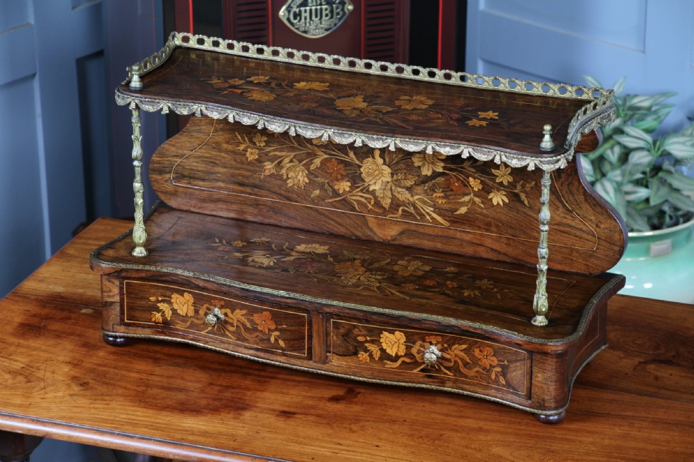 A French Napoleon III rosewood tabletop etagere featuring two tiered shelves decorated with floral marquetry, gilt metal mounts, a gallery rail, and two small base drawers. View XV
