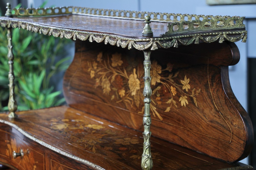 A French Napoleon III rosewood tabletop etagere featuring two tiered shelves decorated with floral marquetry, gilt metal mounts, a gallery rail, and two small base drawers. View XVII
