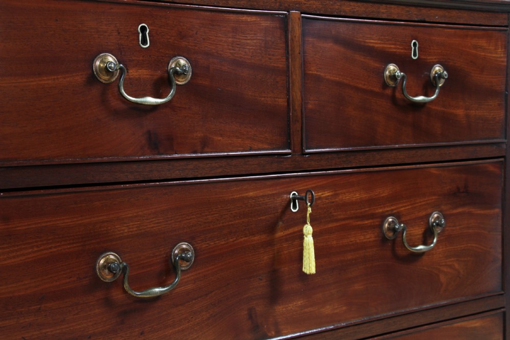 An eighteenth-century Georgian mahogany chest of drawers featuring four drawers with brass swan-neck handles and bracket feet. View IV