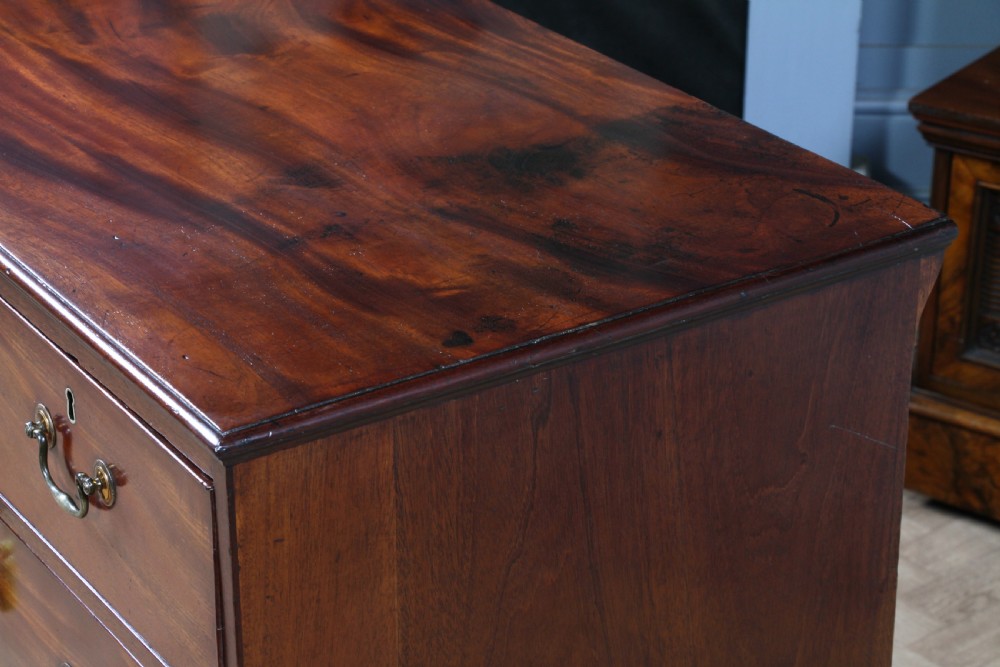 An eighteenth-century Georgian mahogany chest of drawers featuring four drawers with brass swan-neck handles and bracket feet. View X