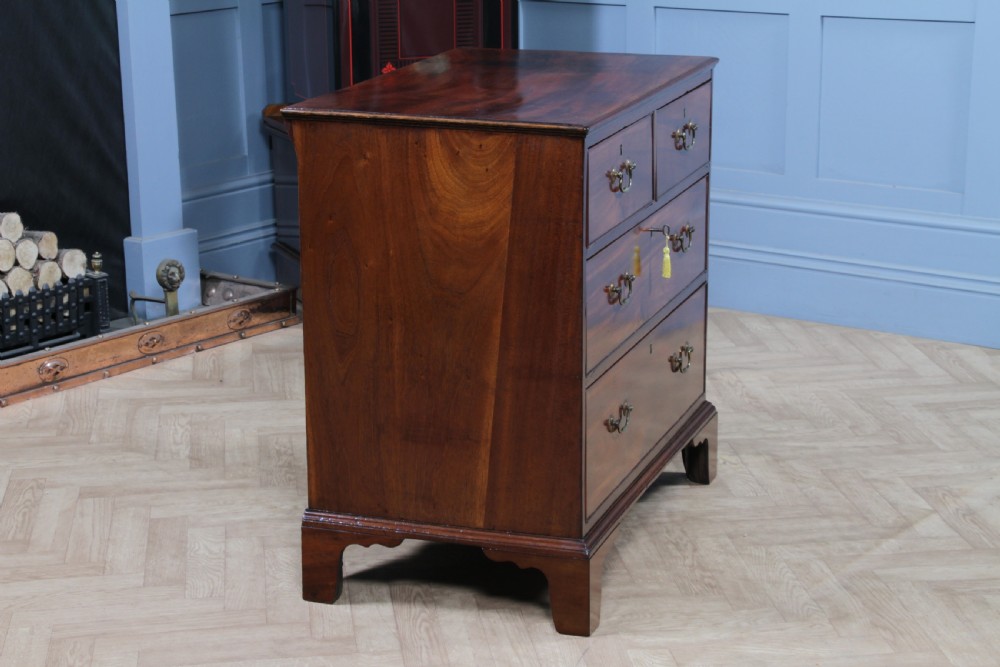 An eighteenth-century Georgian mahogany chest of drawers featuring four drawers with brass swan-neck handles and bracket feet. View XX