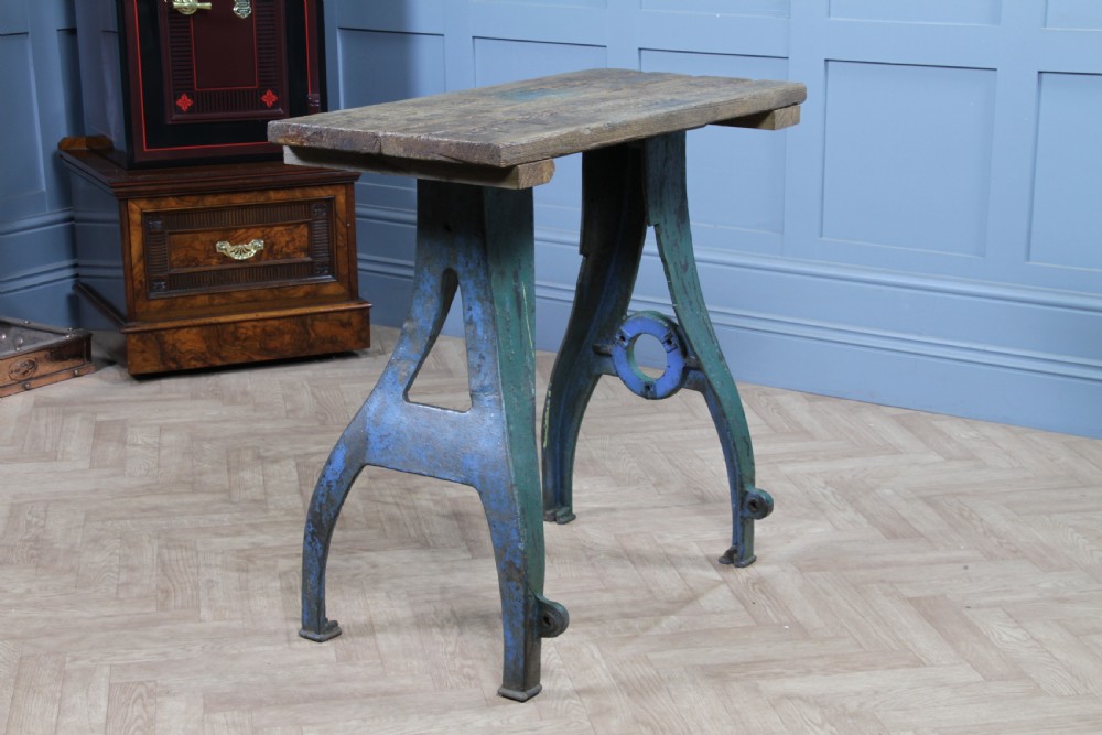 An industrial console table featuring distressed blue painted cast iron machinery legs supporting a rectangular reclaimed pine top. View VIII