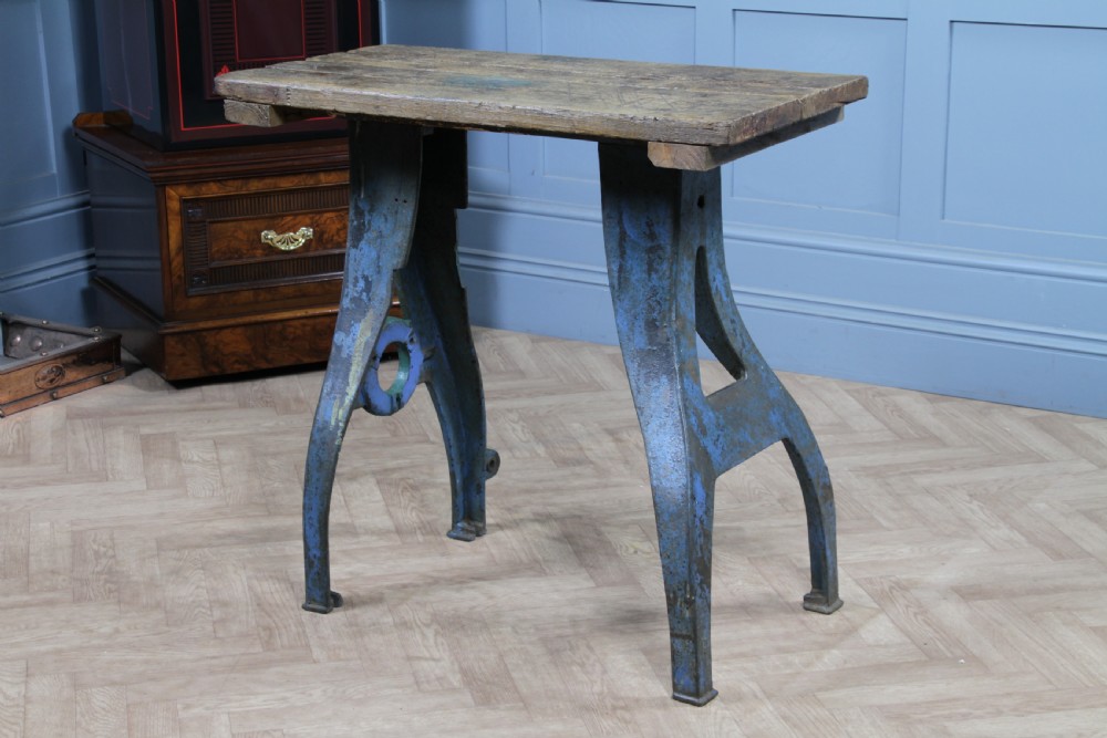 An industrial console table featuring distressed blue painted cast iron machinery legs supporting a rectangular reclaimed pine top. View IX