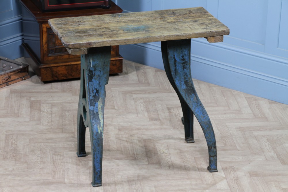 An industrial console table featuring distressed blue painted cast iron machinery legs supporting a rectangular reclaimed pine top. View X