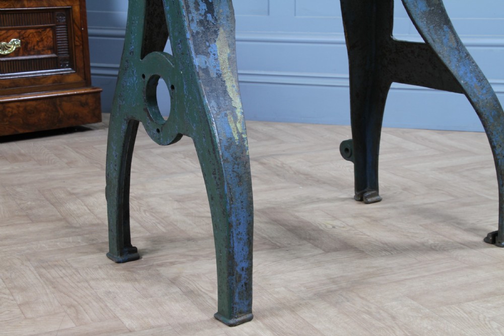 An industrial console table featuring distressed blue painted cast iron machinery legs supporting a rectangular reclaimed pine top. View XII