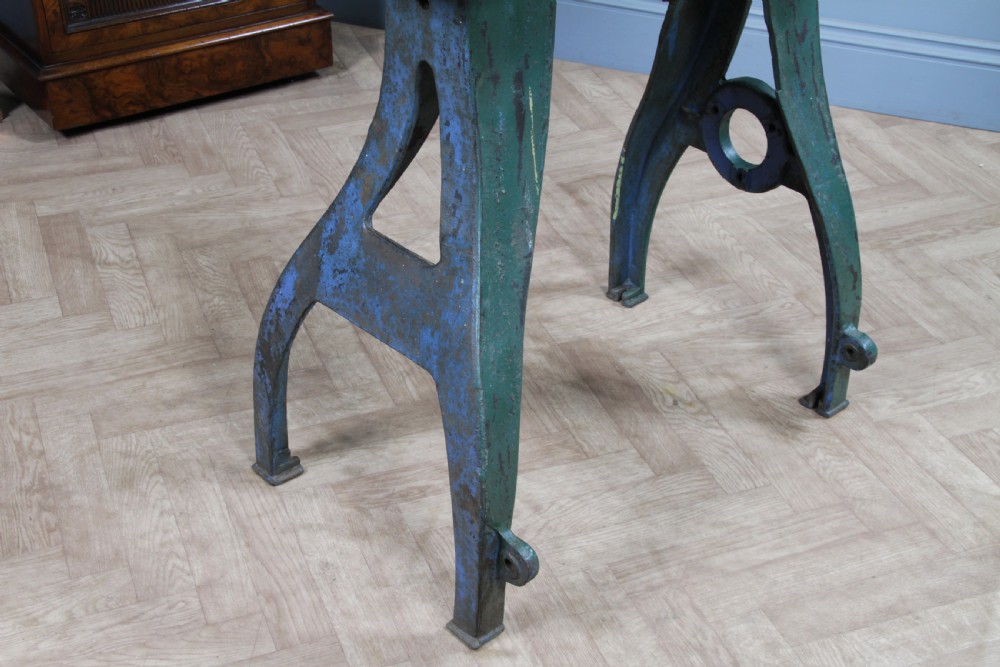 An industrial console table featuring distressed blue painted cast iron machinery legs supporting a rectangular reclaimed pine top. View XIV