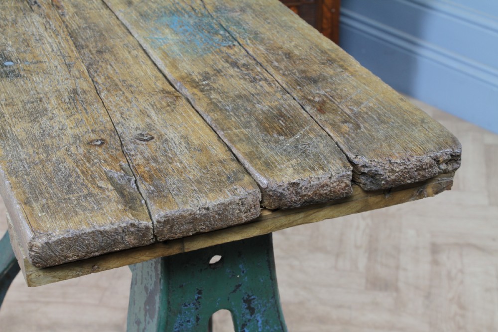 An industrial console table featuring distressed blue painted cast iron machinery legs supporting a rectangular reclaimed pine top. View XVII