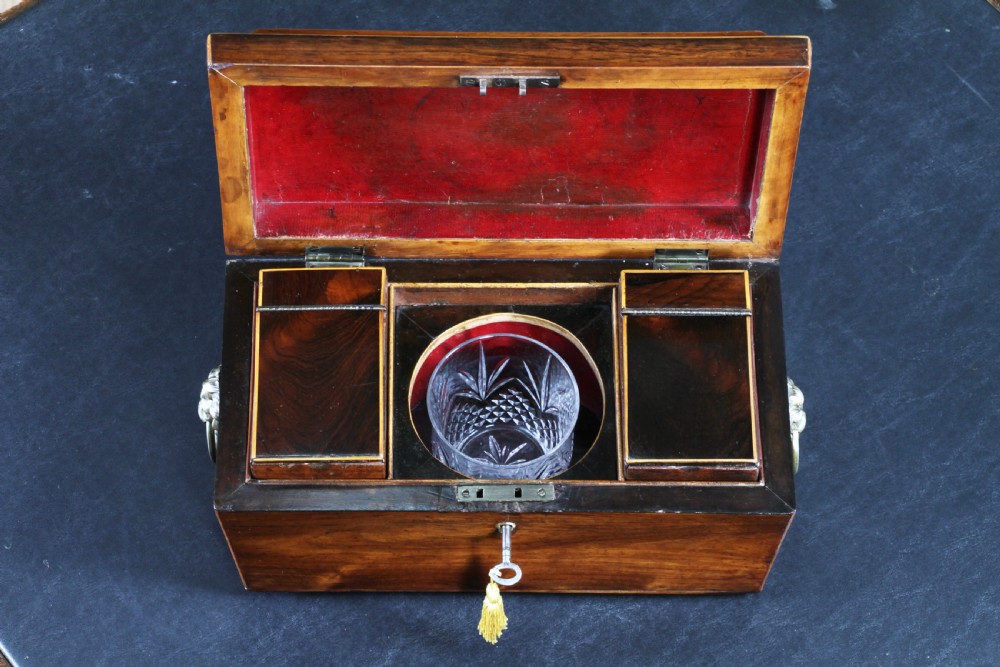 A Georgian rosewood sarcophagus-form tea caddy featuring stringing inlay, brass lion-mask side handles, and a keyhole with a tasselled key. View III