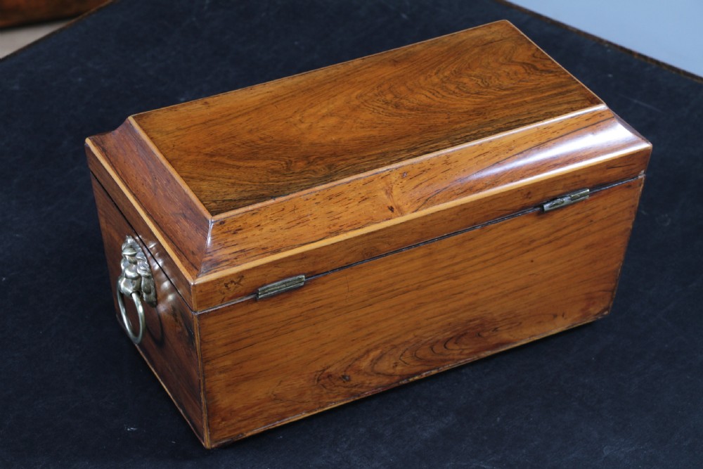 A Georgian rosewood sarcophagus-form tea caddy featuring stringing inlay, brass lion-mask side handles, and a keyhole with a tasselled key. View XI