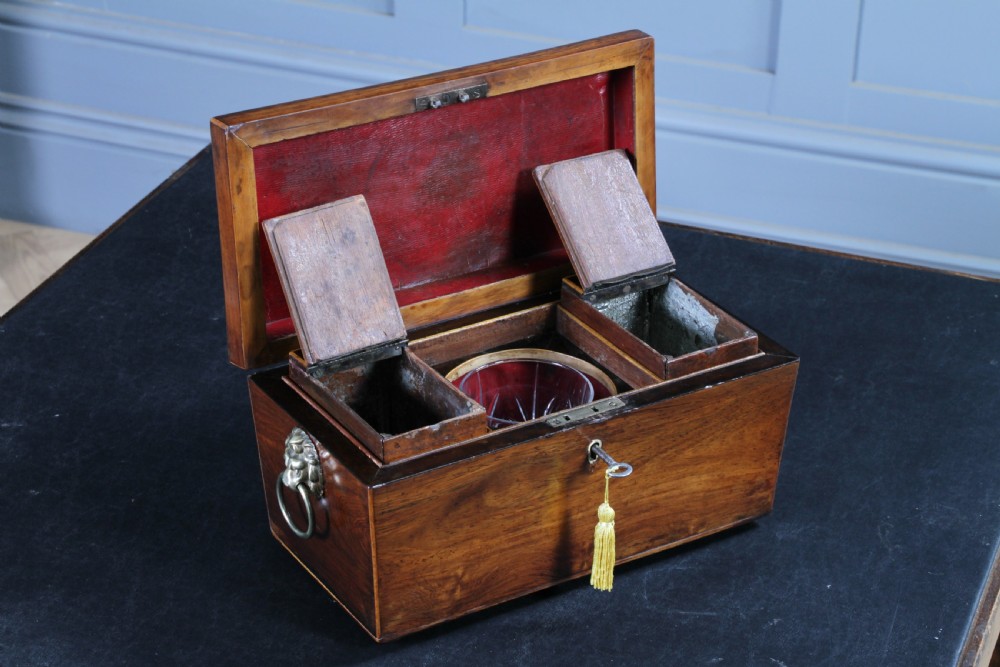 A Georgian rosewood sarcophagus-form tea caddy featuring stringing inlay, brass lion-mask side handles, and a keyhole with a tasselled key. View XII