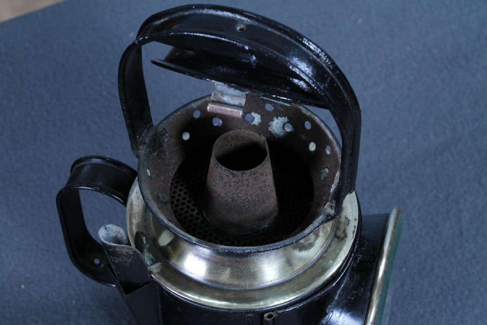 An antique black painted iron GWR railway hand lantern featuring a circular glass lens, top handle, brass accents, and a red painted band near the base. View XV