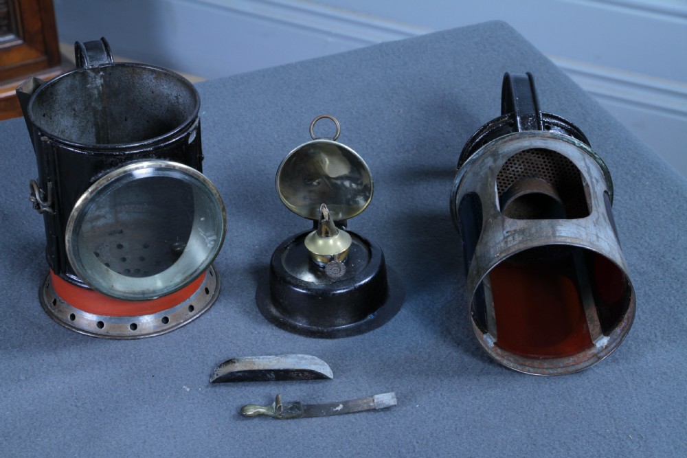 An antique black painted iron GWR railway hand lantern featuring a circular glass lens, top handle, brass accents, and a red painted band near the base. View XVIII