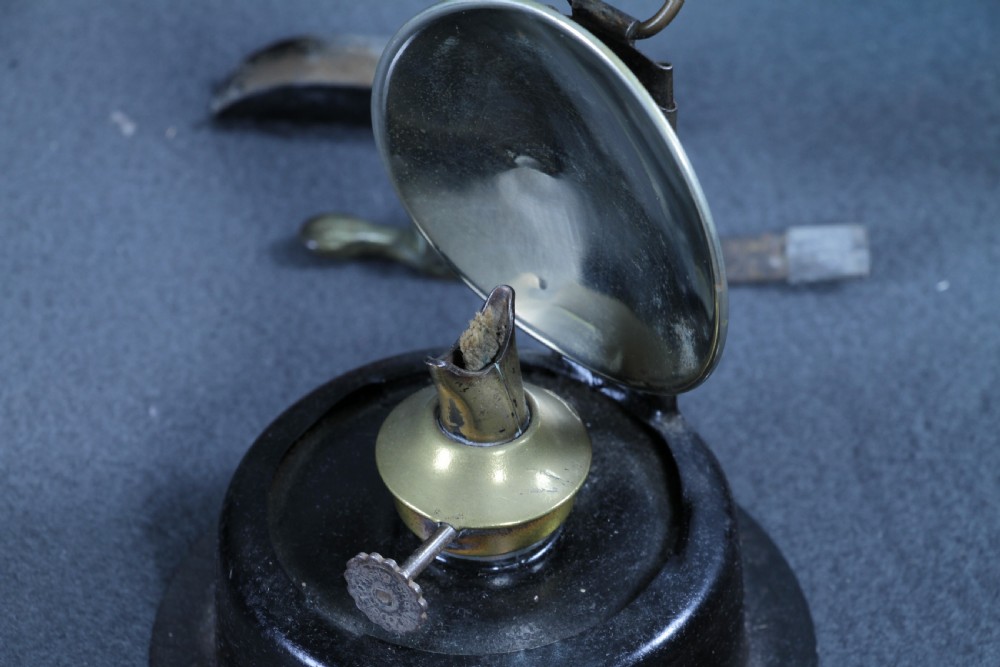 An antique black painted iron GWR railway hand lantern featuring a circular glass lens, top handle, brass accents, and a red painted band near the base. View XXI