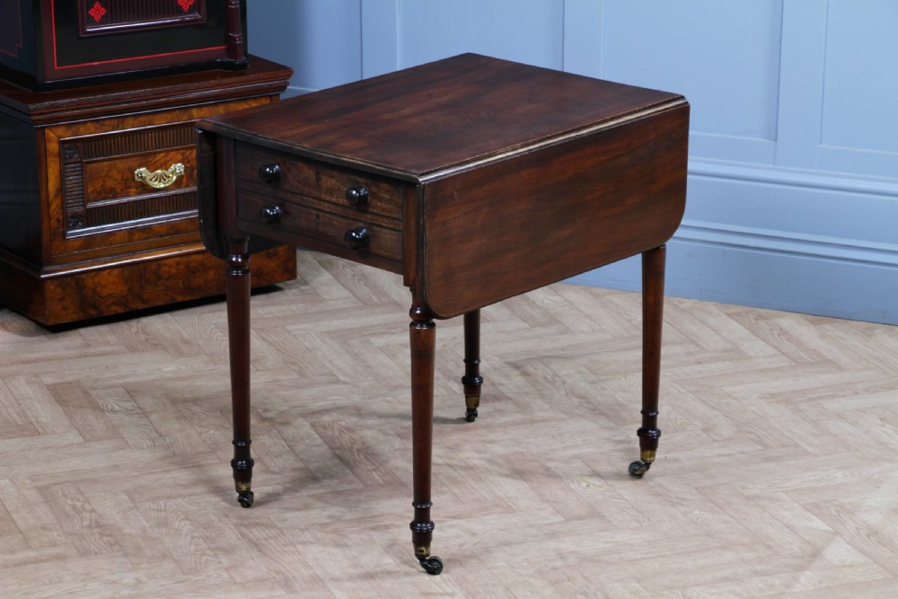 A George III mahogany Pembroke table featuring drop leaves, turned legs on brass castors, and an open drawer fitted with a green baize writing slope and compartments. View VII