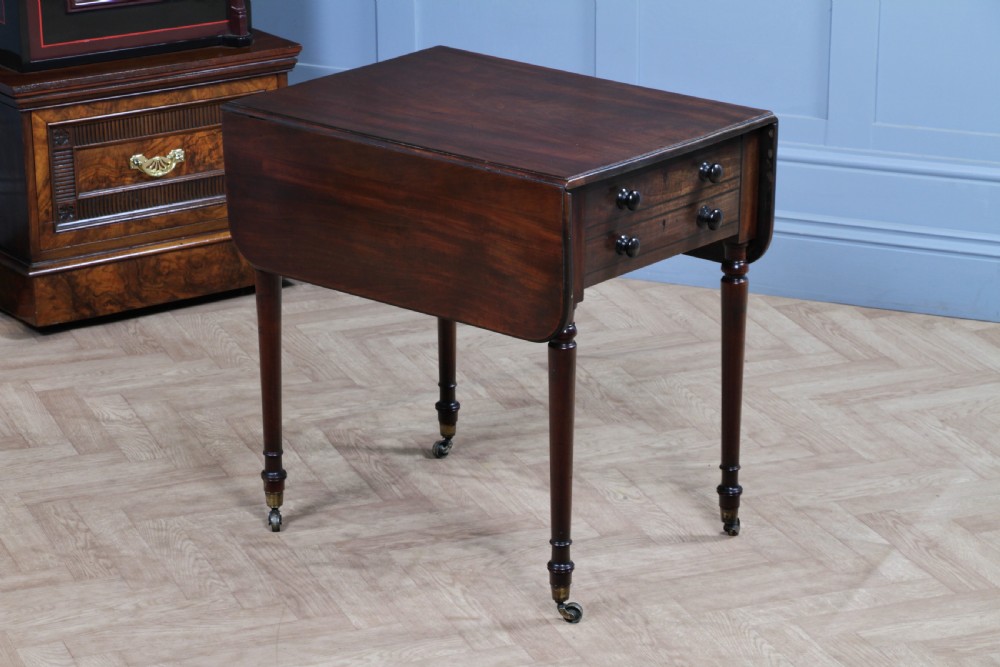 A George III mahogany Pembroke table featuring drop leaves, turned legs on brass castors, and an open drawer fitted with a green baize writing slope and compartments. View VIII