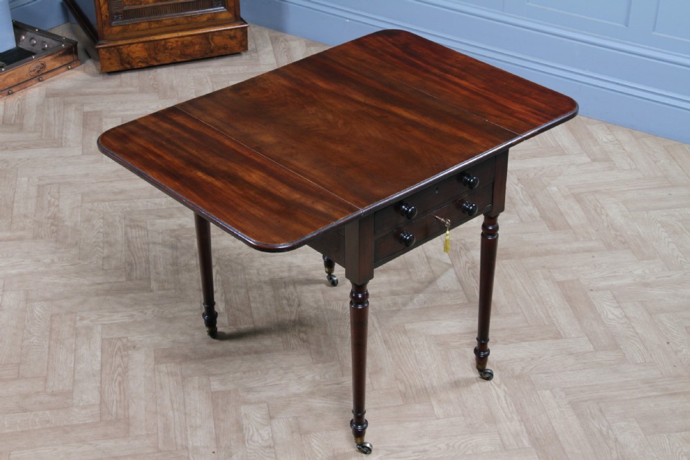 A George III mahogany Pembroke table featuring drop leaves, turned legs on brass castors, and an open drawer fitted with a green baize writing slope and compartments. View XII