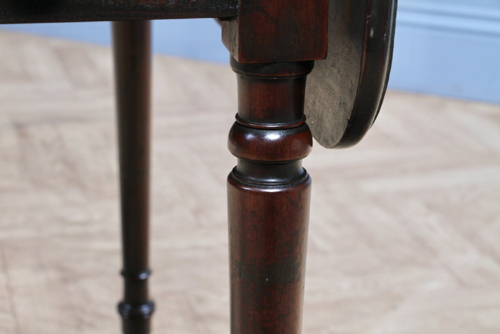 A George III mahogany Pembroke table featuring drop leaves, turned legs on brass castors, and an open drawer fitted with a green baize writing slope and compartments. View XXIII