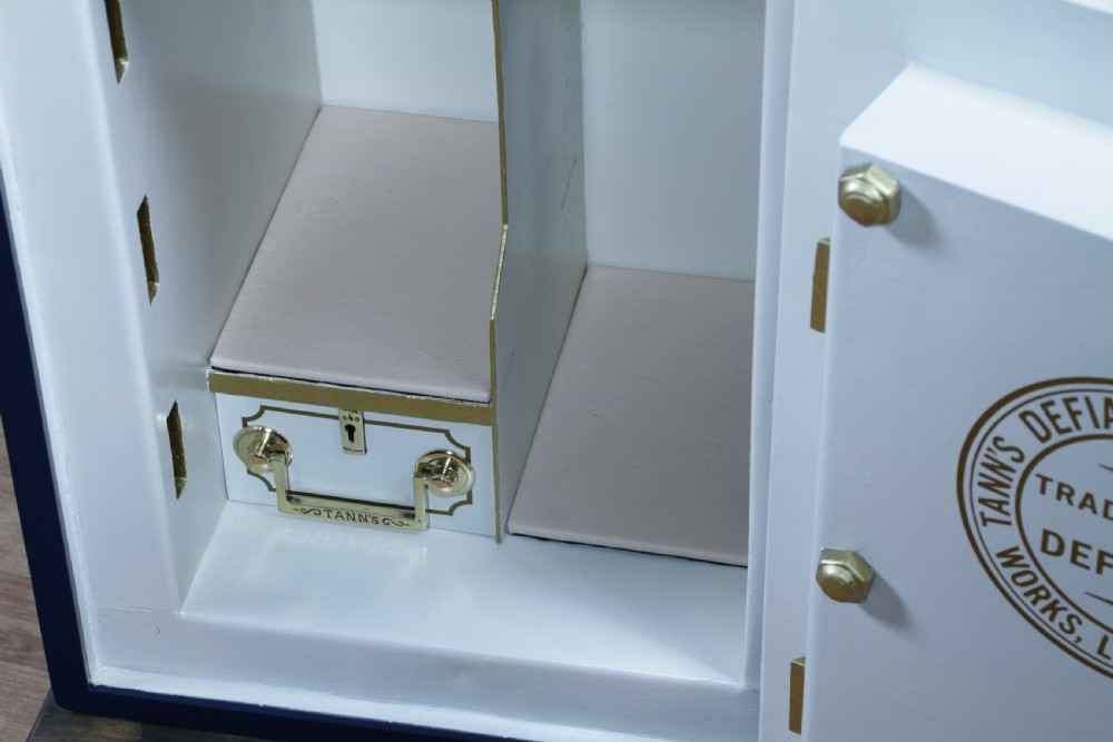 A restored Victorian navy blue and black cast iron safe featuring polished brass hardware and a makers plaque, raised on a dark wooden plinth. View VII