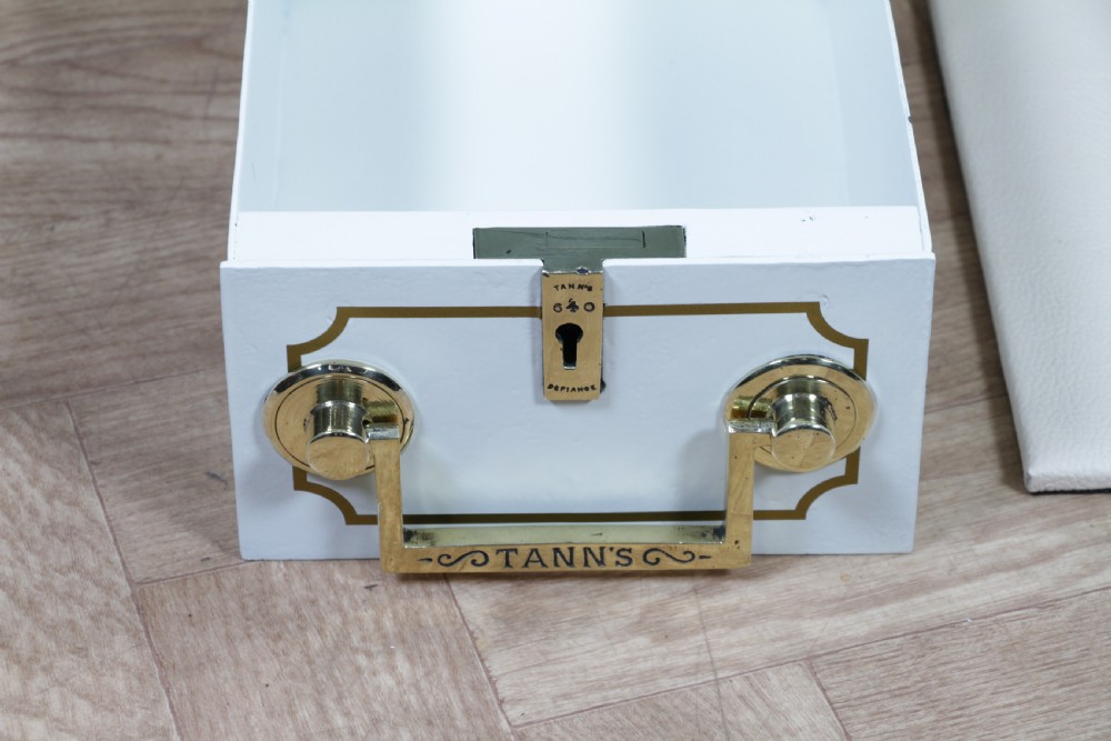 A restored Victorian navy blue and black cast iron safe featuring polished brass hardware and a makers plaque, raised on a dark wooden plinth. View VIII